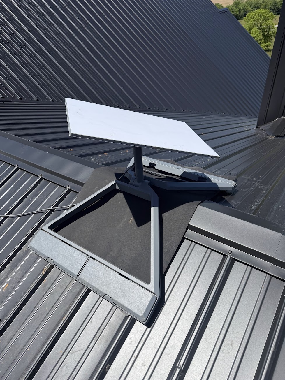 Starlink dish supported by a ridgeline mount across a metal roof peak
