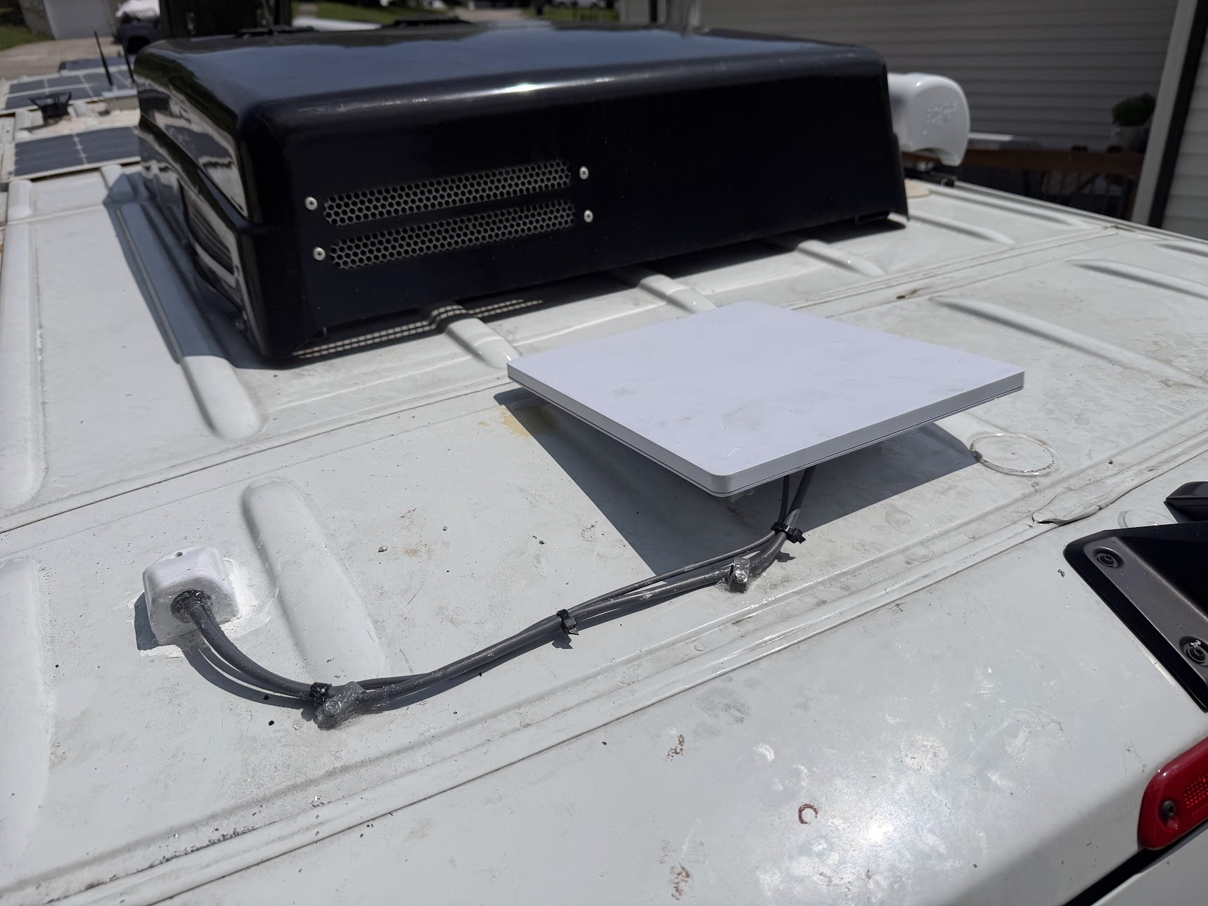 Starlink Mini mounted on an RV roof with its cable following the roof to an entry fitting