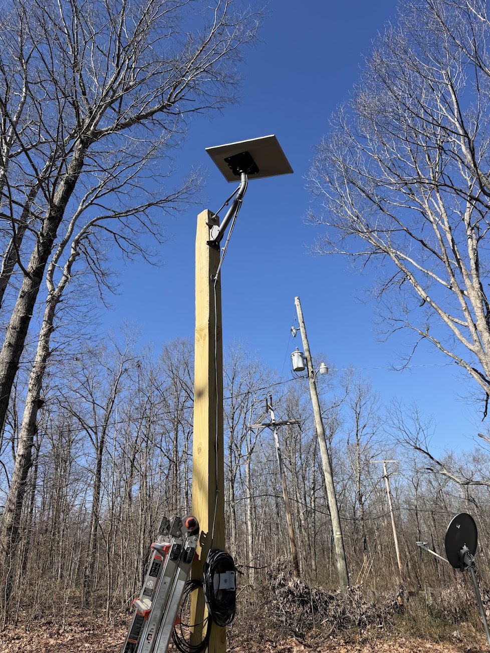 Starlink dish installed high on a custom wooden pole in a wooded area
