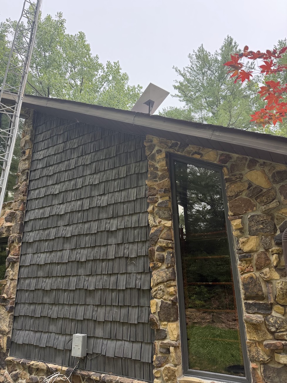Starlink dish installed along the roofline of a stone and cedar home
